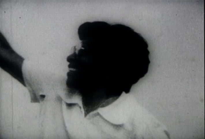 A still from Fannie's Film featuring ablack woman in sillouhette smilling as she reaches to up to the left at something off screen.