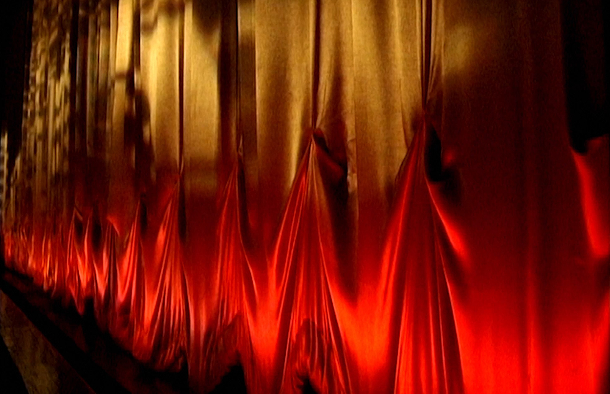 A red & gold curtain, draped across a stage.