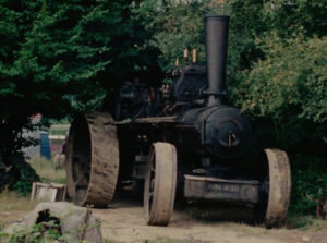 A large steam engine sits in a wooded clearing